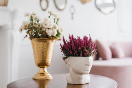 Decorative flowers in elegant golden and white head-shaped vases.