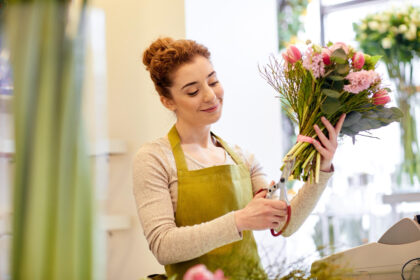 Florist arranging a bouquet of flowers with care and focus.