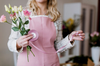 Florist wearing a pink apron arranging flowers with a stethoscope.