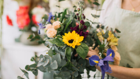 A vibrant bouquet featuring a bright sunflower among other colorful flowers and greenery.