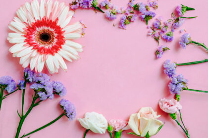 A floral heart frame on a pink background with various colorful flowers.