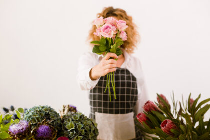 Person holding pink flowers in front of their face.