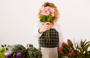Person holding pink flowers in front of their face.