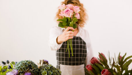 Person holding pink flowers in front of their face.