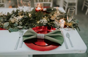 Elegant holiday table setting with green napkin and red plate.