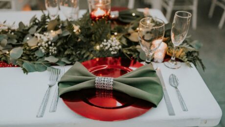 Elegant holiday table setting with green napkin and red plate.